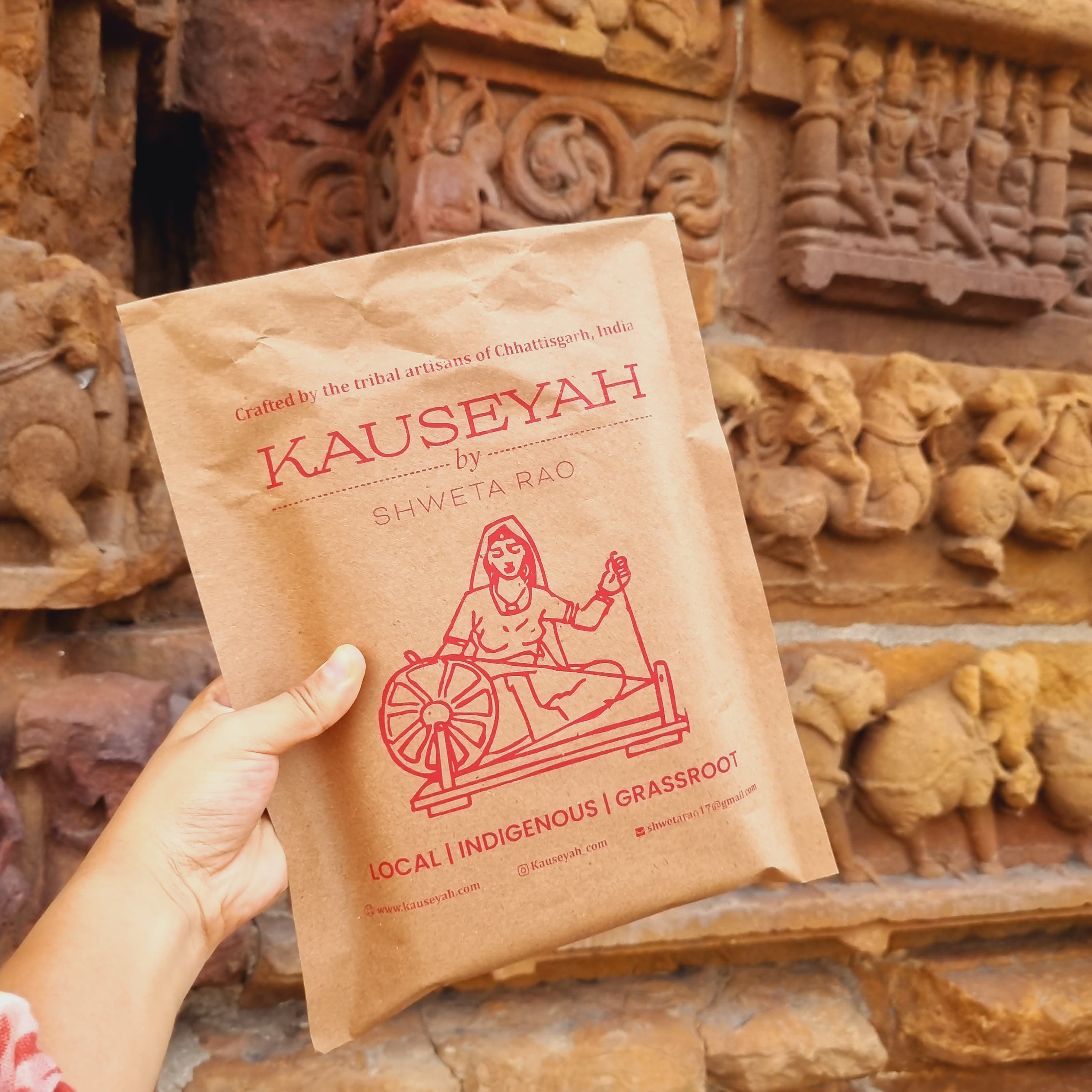 Kauseyah branded kraft envelope against ancient stone temple carvings