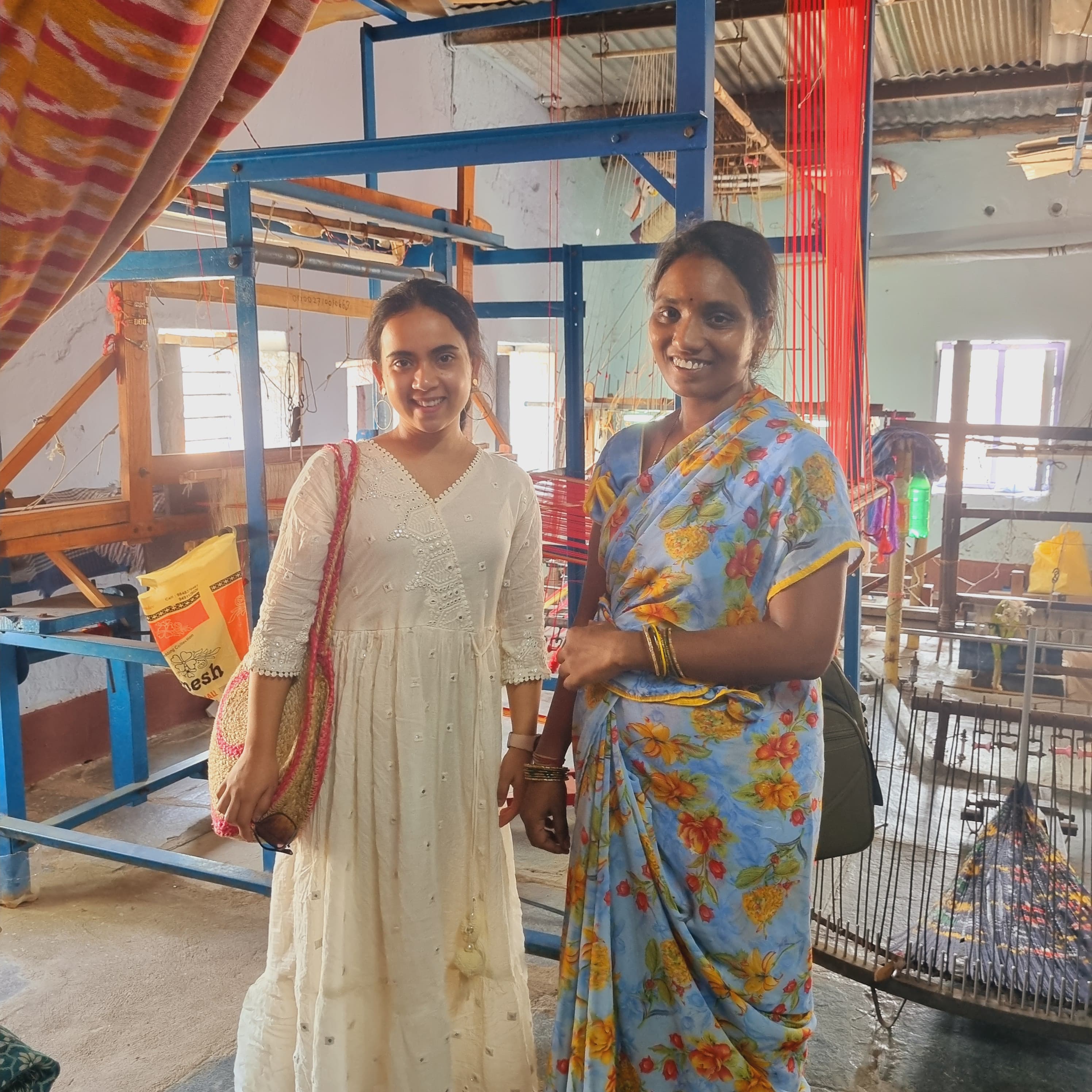 Two women smiling together in a handloom weaving workshop