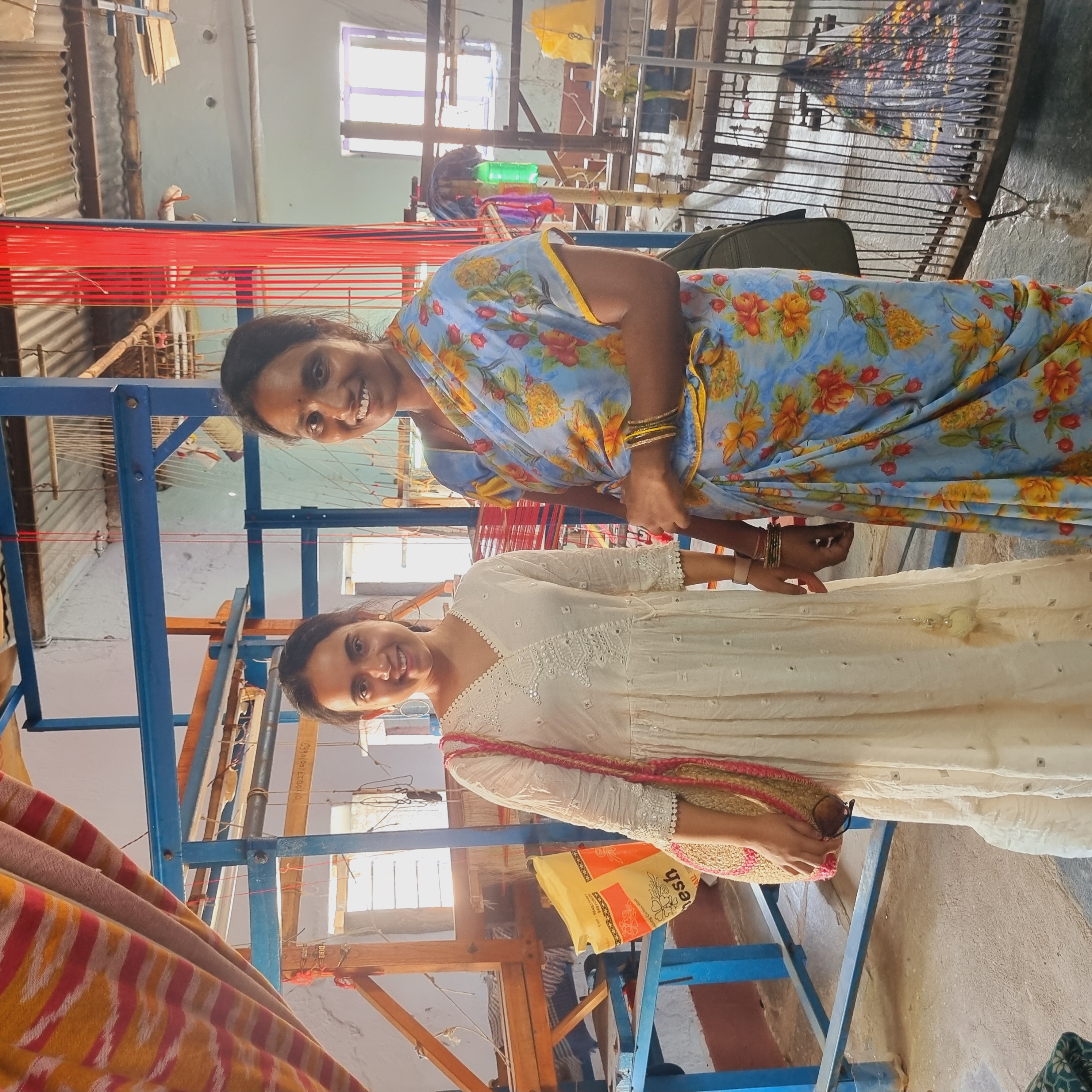 Two women smiling together in a handloom weaving workshop