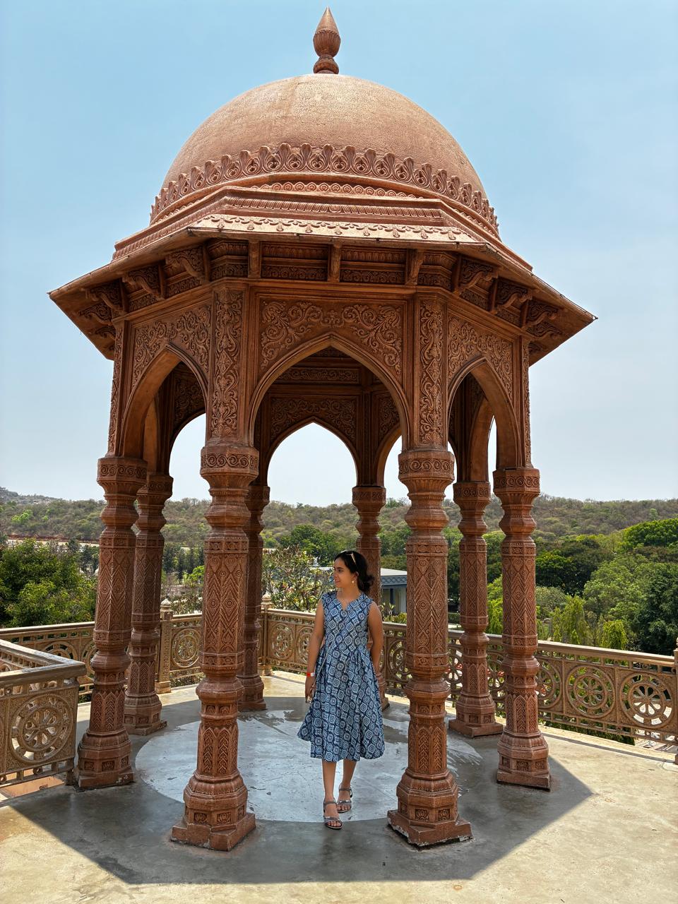 Woman standing inside an ornate carved stone chhatri pavilion
